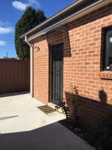 a brick building with a gate on the side of it at Grannyflat in Bankstown