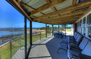 a screened porch with chairs and a table and a view of the ocean at Stanley View Beach House in Stanley