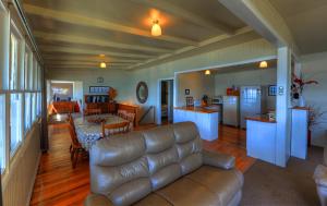 a living room with a leather couch and a kitchen at Stanley View Beach House in Stanley