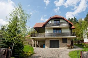 a house with a gambrel roof and a driveway at Klimkówka 96 - Dom w górach nad jeziorem in Klimkówka