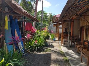 a patio with a bunch of plants and a building with surfboards at Red Island Bungalows in Pasanggaran