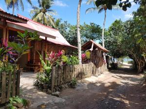 a house with a fence and palm trees at Red Island Bungalows in Pasanggaran