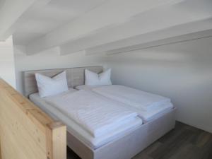 un letto bianco con lenzuola e cuscini bianchi di Pension Weber a Erfurt