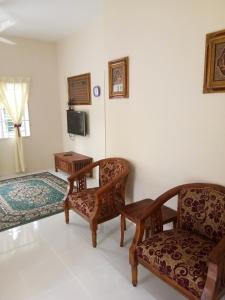 a living room with two chairs and a television at Homestay AZMI ZITA in Kuala Terengganu