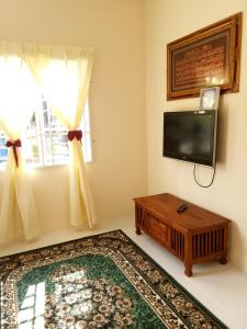 ein Wohnzimmer mit einem Flachbild-TV und einem Tisch in der Unterkunft Homestay AZMI ZITA in Kuala Terengganu