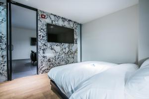 a bedroom with a white bed and a tv on a wall at Rivertain Hotel in Daegu