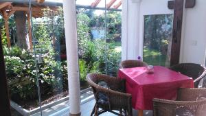 une table avec une toile de table rose assise sur une terrasse couverte dans l'établissement Gästehaus im Malerwinkel-Rhodt, à Rhodt unter Rietburg