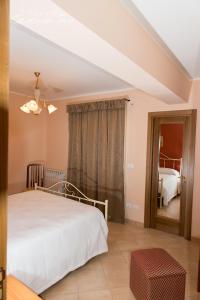 a bedroom with a white bed and a mirror at Casa Sofia Vacanze A Montalbano Elicona in Montalbano Elicona