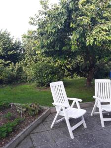 two white chairs sitting on a patio in a garden at Ferienwohnung Mayer in Kirchheim am Ries
