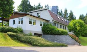 ein großes weißes Haus mit Büschen und Bäumen in der Unterkunft Ferienhaus Vier Jahreszeiten in Frauenwald