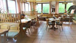a restaurant with wooden tables and chairs and windows at Privatzimmer Lehmann in Kottmar