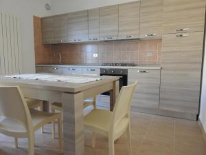 a kitchen with a wooden table and chairs and a counter at Soggiorno Ulivi in Altino
