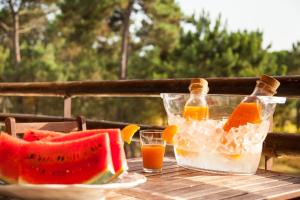 a table with two glasses of juice and a bowl of fruit at bwelcome aroeira beach & golf in Charneca