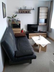 a living room with a black leather couch and a table at Ferienwohnung Mey in Rathmannsdorf