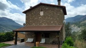 una casa de piedra con techo con montañas al fondo en Casa Montenegro en Las Colladas