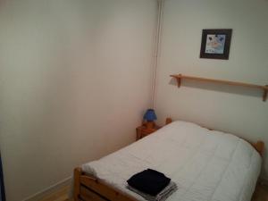 ein kleines Schlafzimmer mit einem weißen Bett und einem Regal in der Unterkunft Appartements Le Clos des Gentianes in Allevard