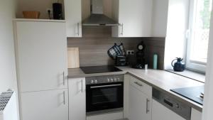 a kitchen with white cabinets and a stove top oven at Ferienwohnung Waterkant in Kappeler Niederstrich +4 photos