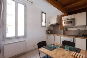 uma cozinha com armários brancos e uma mesa de madeira em Aoustin em Nice