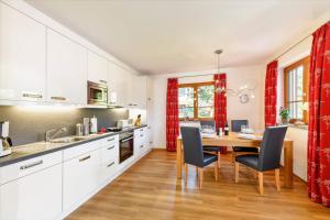una cocina con armarios blancos y una mesa con sillas. en Landhaus Stillachaue, en Oberstdorf