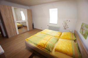 Schlafzimmer mit einem Bett mit gelber Bettwäsche und einem Spiegel in der Unterkunft Ferienwohnung Michels in Bernkastel-Kues