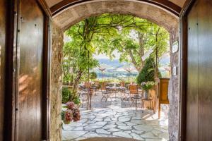 ムスティエ・サント・マリーにあるLa Bastide De Moustiers - Hôtel et Restaurant - Teritoriaのテーブルと椅子のあるパティオにつながるアーチ道