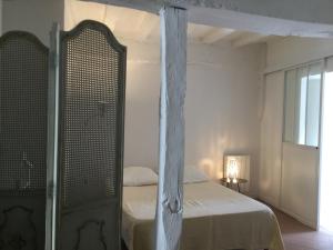 a white bedroom with a bed and a window at La petite maison d’à côté, au n°11 in Saint-Aignan
