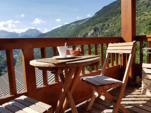 a wooden table and chair on a balcony with mountains at Arpege Des Neiges in Sainte-Foy-Tarentaise