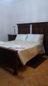 1 cama con marco de madera y almohadas blancas en Crisam, en Sabaudia