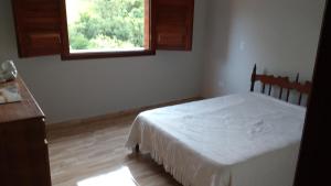 a bedroom with a white bed and a window at Casa em São Tomé das Letras in São Thomé das Letras