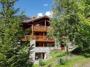 a large wooden house with a deck on a hill at Arpege Des Neiges in Sainte-Foy-Tarentaise