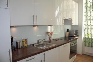 a kitchen with white cabinets and a sink at govienna - City Center Apartments in Vienna