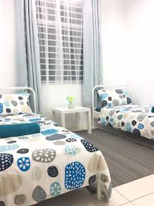 a bedroom with two beds with blue and white pillows at Ceri Merah Homestay in Kuantan
