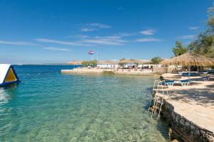 a beach with chairs and umbrellas in the water at Holiday Park Mandrice in Mandre