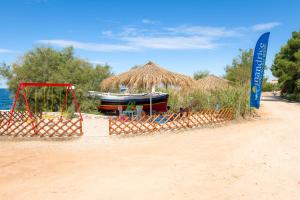 a beach with a boat and a straw hut at Holiday Park Mandrice in Mandre