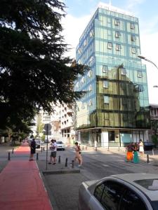 people walking on a city street with a tall building at Hotel Green Glass in Batumi
