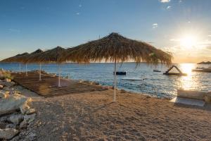 a beach with a large straw umbrella and the ocean at Holiday Park Mandrice in Mandre