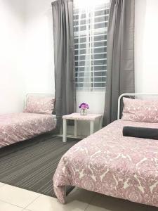 a bedroom with two beds and a table and a window at Ceri Merah Homestay in Kuantan