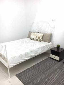 a white bed with pillows and a table in a room at Ceri Merah Homestay in Kuantan