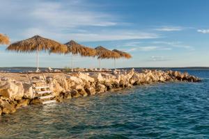 a group of straw umbrellas and chairs on a beach at Holiday Park Mandrice in Mandre
