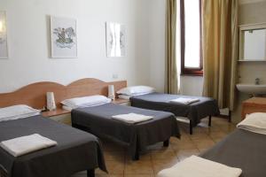 una camera ospedaliera con tre letti e un lavandino di Hotel Alba a Milano