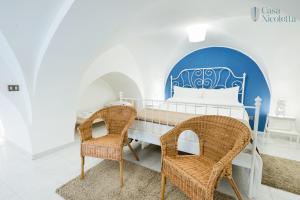 um quarto com uma cama e 2 cadeiras de vime em Casa Nicoletta em Noci