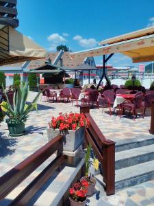 a patio with tables and chairs and flowers in pots at B&B Izvor in Kosjeric