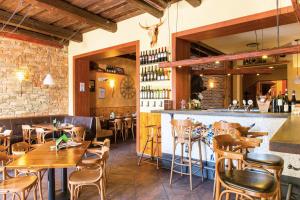 restauracja z drewnianymi stołami i krzesłami oraz barem w obiekcie Hotel Roudna w Pilznie