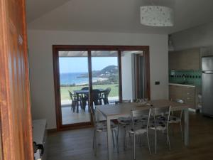 a kitchen and dining room with a table and chairs at La Costa Est Villa con Vista Mare in Ogliastra Sardegna in Tertenìa