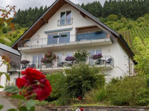 ein weißes Haus mit Balkonen und einer roten Blume in der Unterkunft Gästehaus FALKLAY in Burg (an der Mosel)