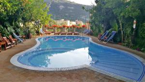 a large blue swimming pool with chairs and trees at Residence Villaggio Verde in Sorrento