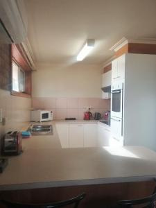 La cuisine est équipée de placards blancs et d'un réfrigérateur blanc. dans l'établissement Bell Motel, à Melbourne