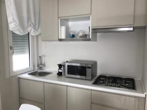 una pequeña cocina con microondas y fregadero en Stunning Apartment 300mt from the beach en Forte dei Marmi
