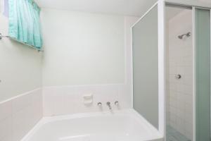 a white bathroom with a tub and a shower at Ebbtide 7 in Forster