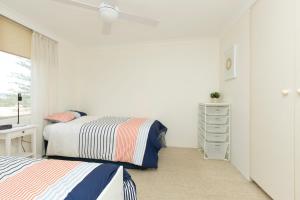 a white bedroom with two beds and a dresser at Beachpoint Unit 501 in Forster